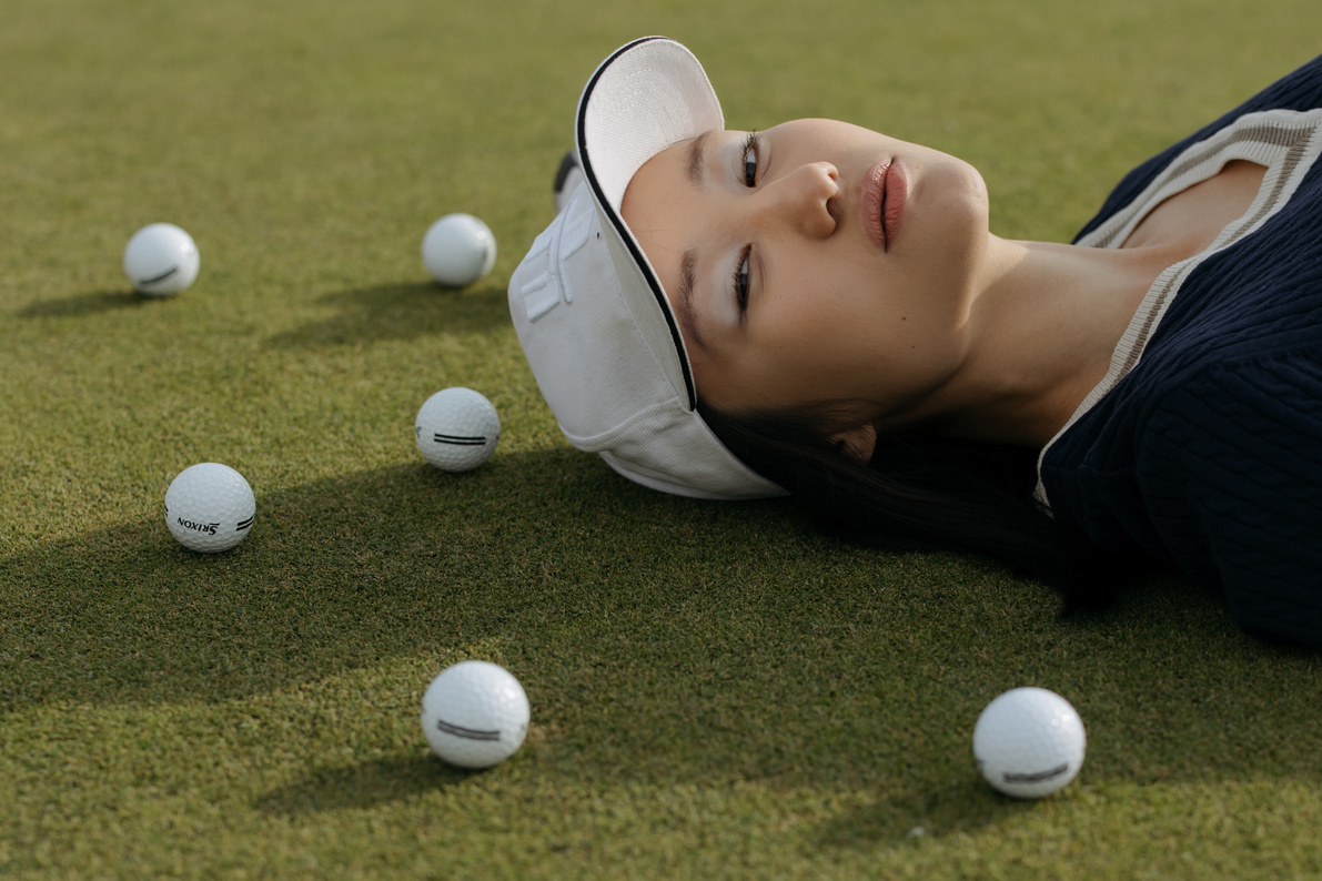 Woman in White Hijab and Black Leather Jacket Lying on Green Grass Field